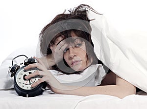 Woman in bed awakening tired holding alarm clock photo