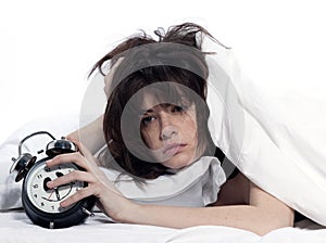 Woman in bed awakening tired holding alarm clock photo