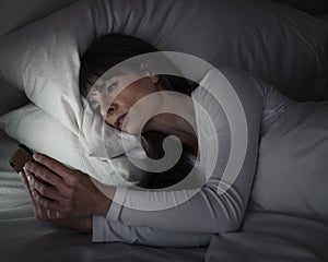 Woman in bed being sentimental on her mobile phone photo