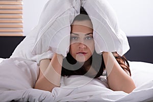 Woman On Bed Covering Her Ear With Bedsheet