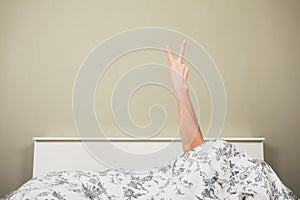 Woman in bed displaying obscene gesture