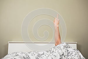 Woman in bed displaying obscene gesture