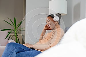 Woman on bed listening music with headphones.