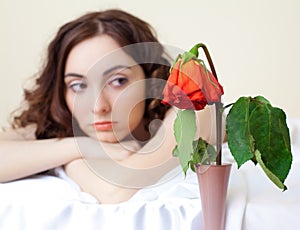 Woman in bed looking on the rose (focus on rose)