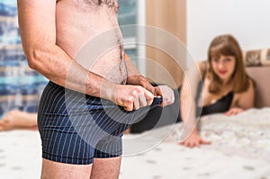 Woman in bed and man in underwear is looking inside