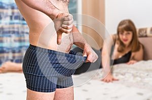 Woman in bed and man in underwear showing thumb down