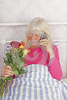 Woman in bed with roses and telephone