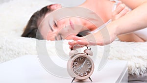 Woman in bed turns off the alarm clock in the morning. Close up alarm clock, selective focus. New day start concept