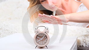 Woman in bed turns off the alarm clock in the morning. the woman does not want to get up early. Alarm clock close-up.