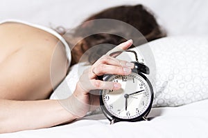 Woman in bed turns off alarm in the morning. woman does not want to wake up early. girl was not sleeping well. Alarm clock