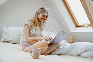 A woman is on a bed using a laptop computer for comfort