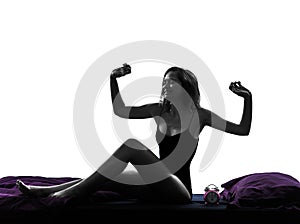 Woman in bed waking up happy stretching silhouette