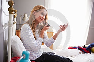 Woman In Bedroom Putting On Make Up In Morning