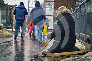 Woman beggar with walking stick asking for money on Moscow street in winter