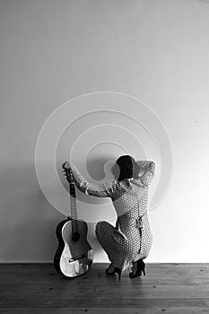 Woman from behind with guitar on a wall