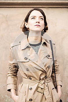 Woman at beige coat with handbag looking up