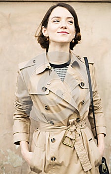 Woman at beige coat with handbag smile sneak