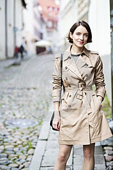 Woman at beige coat with handbag smile stealthily photo