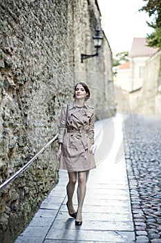 Woman at beige coat near old city wall