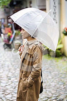 Woman at beige coat and opened white umbrella