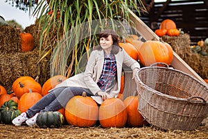 Woman in a beige coat on a pumpkin farm, orange autumn