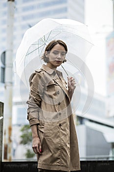 Woman at beige coat on stairs with umbrella