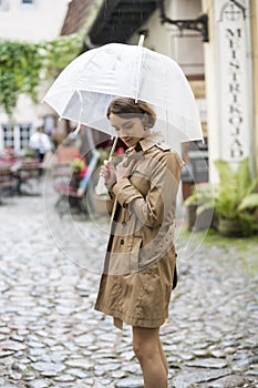 Woman at beige coat with umbrella feels cold