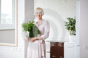 Woman in a beige dress with a bouquet of mint in hand, standing