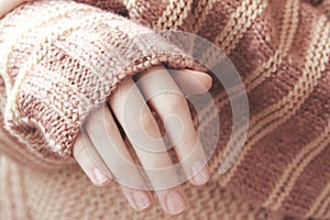Woman in a beige soft warm sweater folded her hands