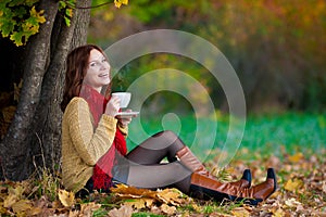 Woman in beige sweater and red scarf drink tea