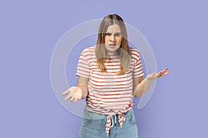 Woman being unhappy and sad, standing raised arms, asking, looking at camera.