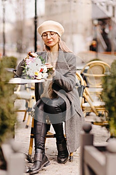 Woman in beret and glasses with a bouquet of flowers