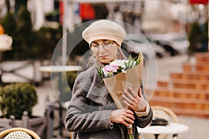 Woman in beret and glasses with a bouquet of flowers