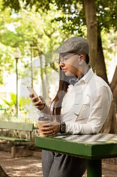 Woman with beret making an on-line purchase with smart phone Outside in park and woods.