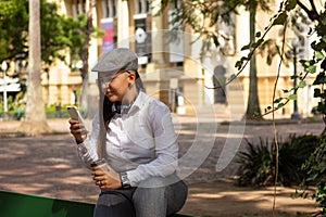 Woman with beret watching photos on mobile smart phone Outside in park and woods. Technology, social media,