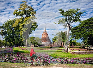 Woman with bicycle near temple in Thailand