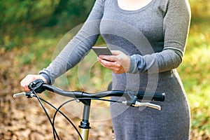 Woman with bicycle texting on mobile phone outdoors