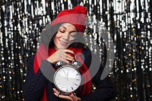 Woman with big alarm clock counting to midnight daydreaming