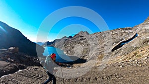 Woman with big backpack hiking with a scenic view on the mountains of Hohe Tauern Alps in Carinthia, Austria, Europe. A lake and