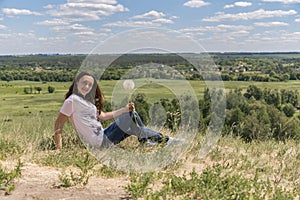 Woman with big dandelion on sky background. Copy space. Summer concept.