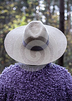 Woman in a big gray hat stands with her back