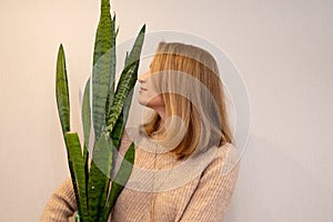 Woman with big houseplant with large green leaves. Love for plants. harmony with nature at home.