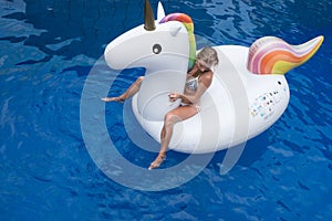 Woman with big inflatable unicorn in the pool