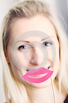 Woman with big paper lips in front of her mouth