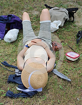 Woman with a big straw hat and she relaxes after picnic on the l