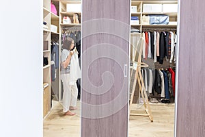 Woman in big walkin closet choosing clothes. modern wardrobe and dressing room with copy space