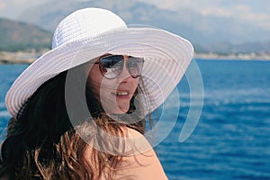 Woman in a big white hat ooks at sea