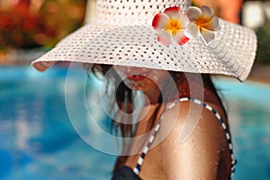 Woman in a big white hat posing near pool