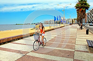 Woman biking on the boulevard along Pocitos beach in Montevideo, Uruguay.