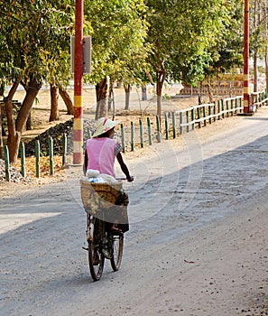 A woman biking on rural road in Bagan, Myanmar